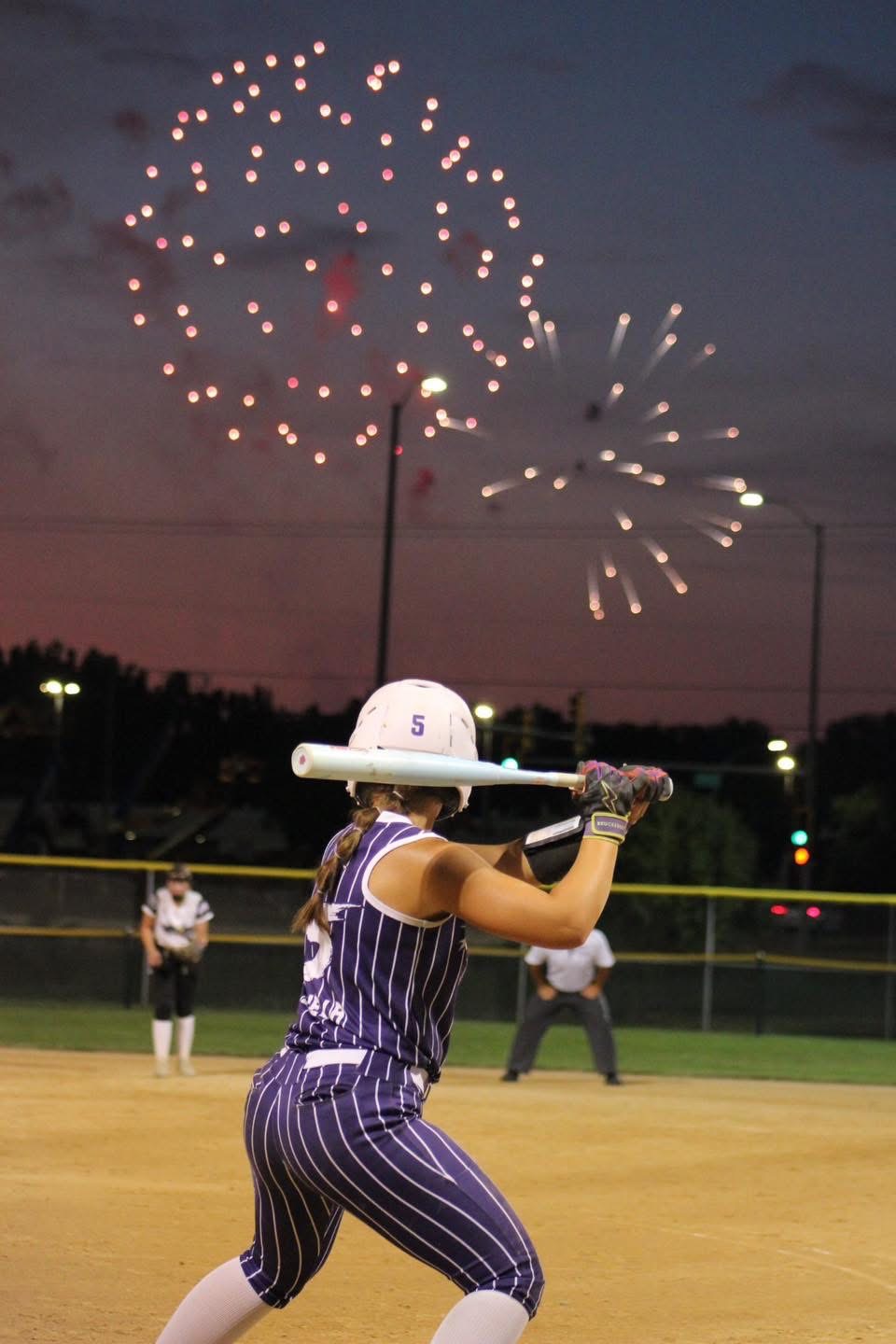Softball player swinging at dusk